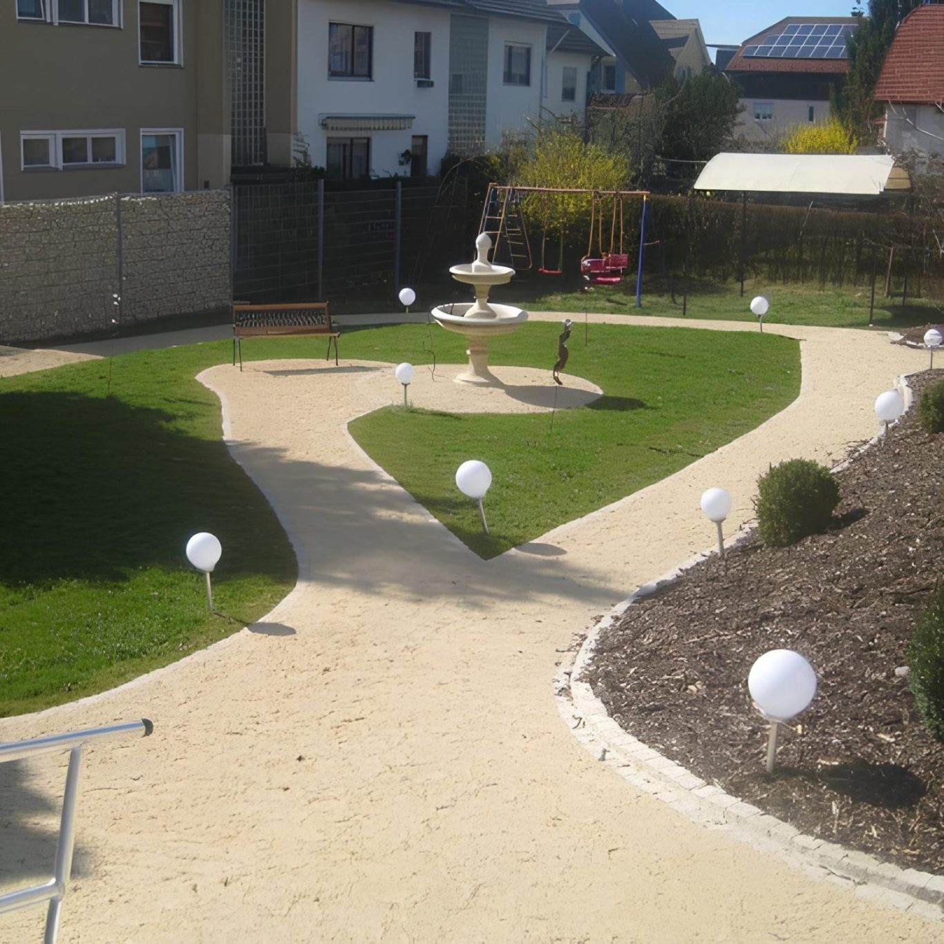 Garten Garten mit Rasen, Pflanzen mit Springbrunnen und einer weißen Kugelbeleuchtung entlang der Wege.