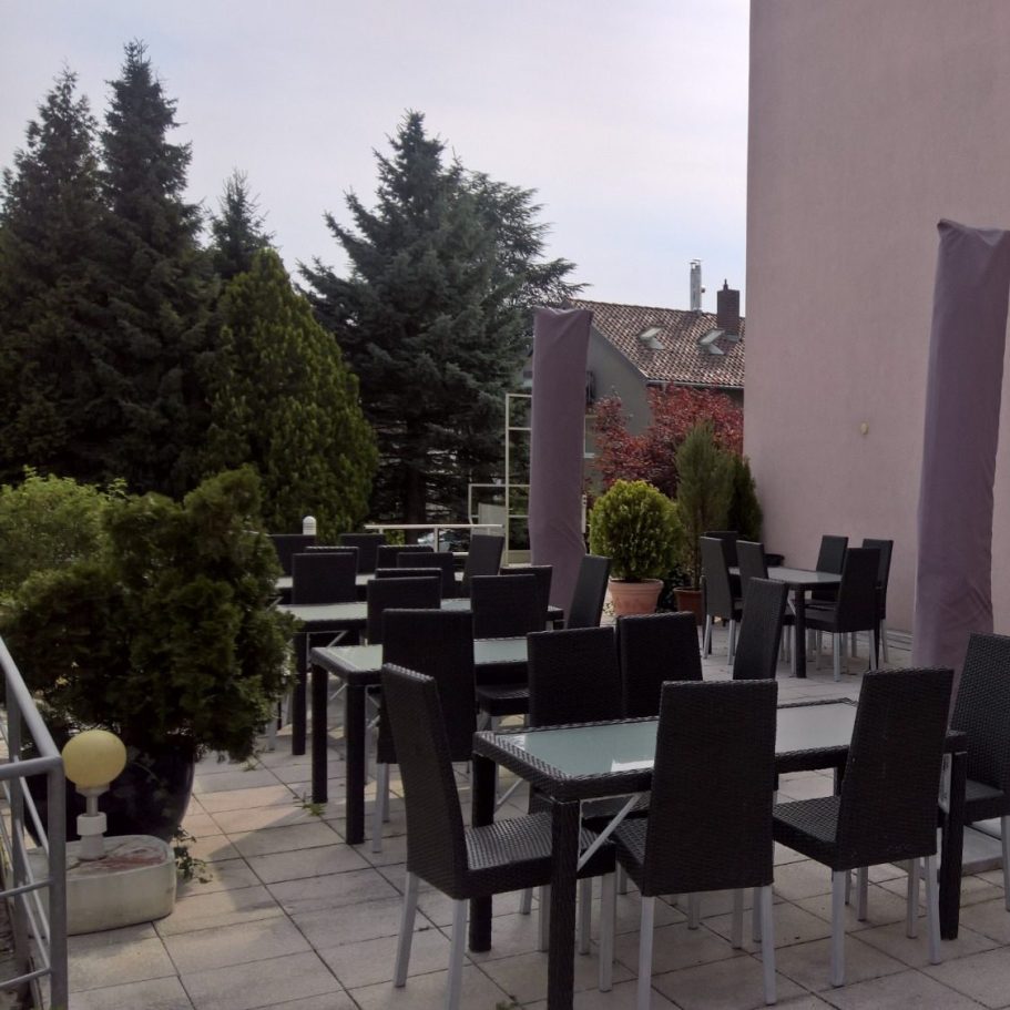 Terrasse Schöne Terrasse mit Tischen und Stühlen, umgeben von Bäumen und Pflanzen.
